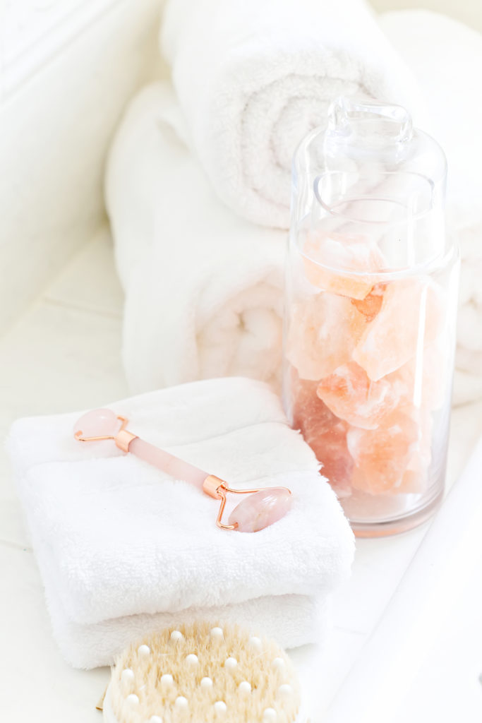A picture of a skin rollers with bath towels, bath salts, and a loofah scrub.
